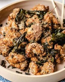 A close shot shows crispy crunchy Taiwanese popcorn chicken with crushed basil leaves served in a light pink big plate.