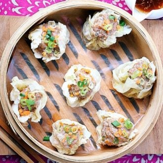 Photo shows Chinese dim sum shumai made with cabbage leaves and served in a bamboo steamer basket