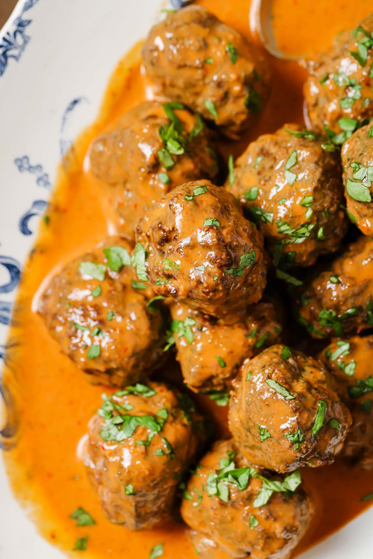 A close shot shows the texture and glossy curry sauce covered Thai meatballs.