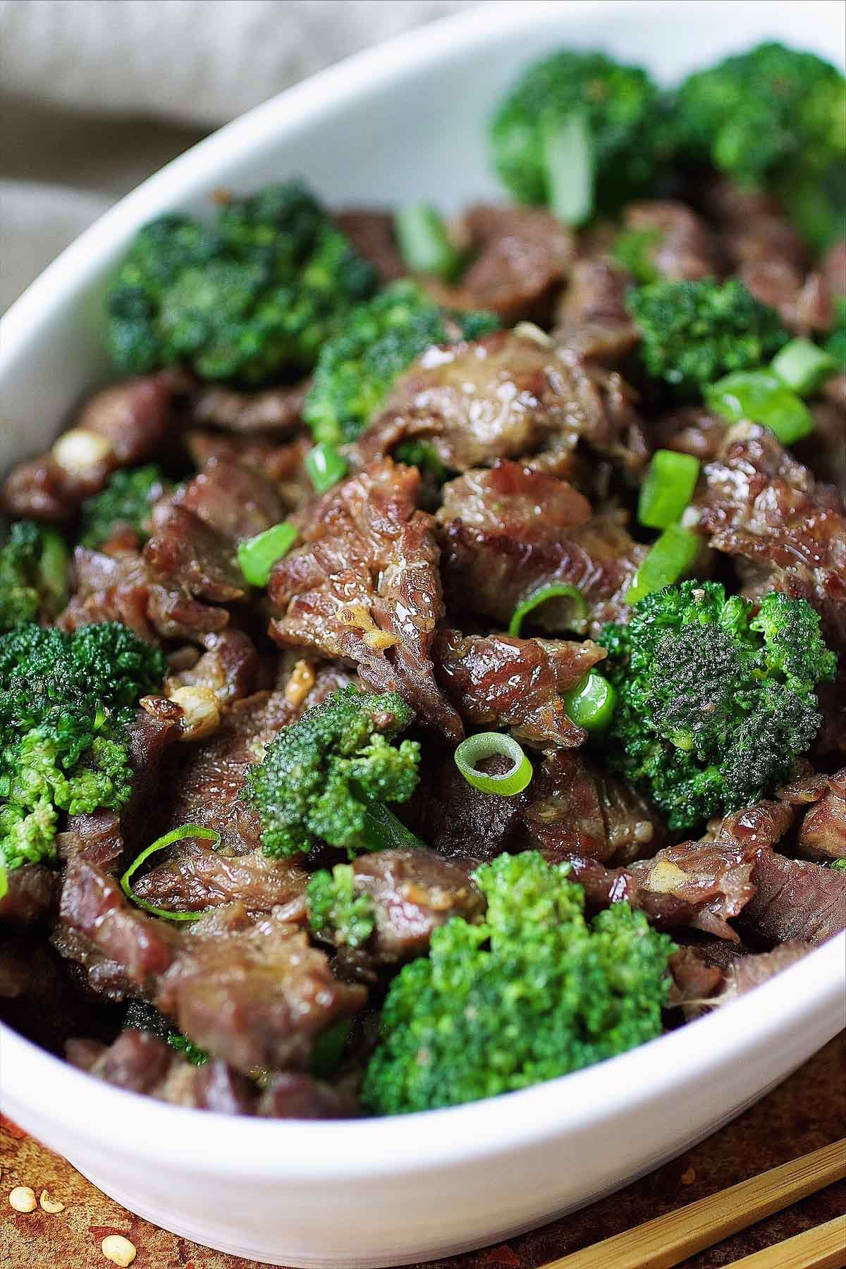 Image shows velveted beef stir fried with crisp broccoli and served in a white color plate.