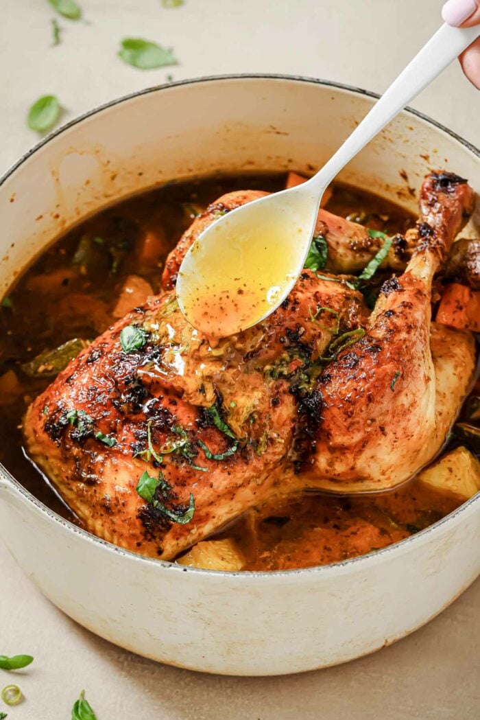 Person demos drizzle the whole roasted chicken with juice from the Dutch oven