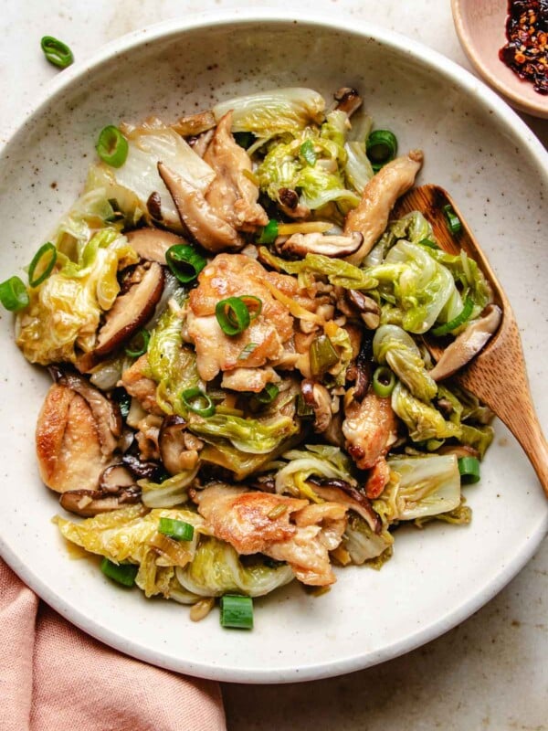 Image shows stir fried napa cabbage with chicken breasts and shiitake served on a white plate