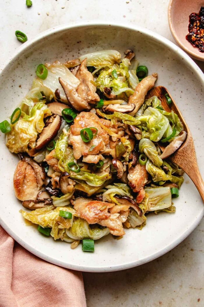 Image shows stir fried napa cabbage with chicken breasts and shiitake served on a white plate