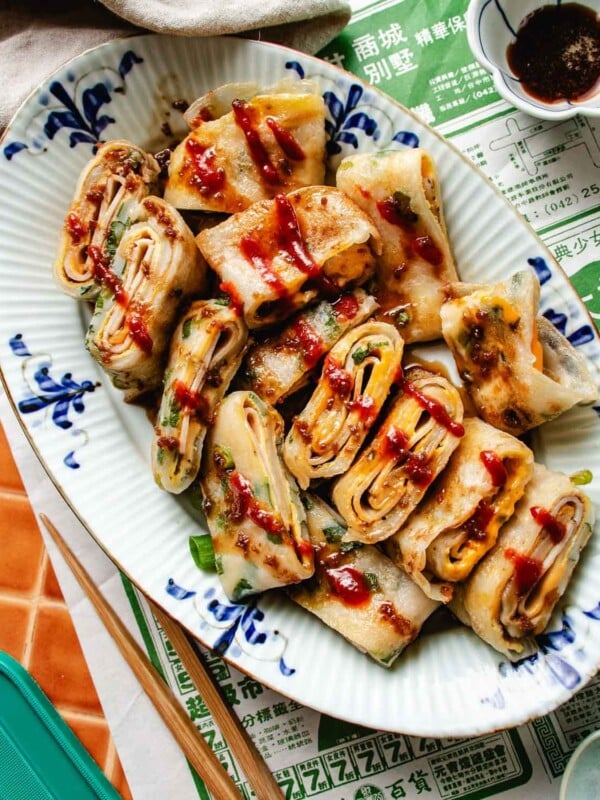 Feature image shows an overhead shot of Taiwanese dan bing served over a blue white color oval plate with sauce drizzled on top.