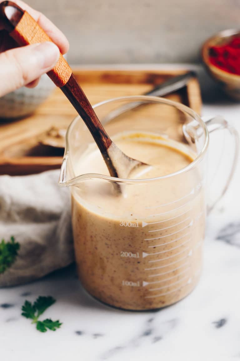 Photo shows creamy peanut Thai sauce in a glass measuring cup
