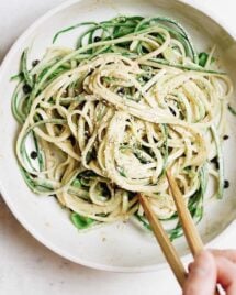 A close shot photo shows cucumber noodles drizzled with thai peanut sauce in a serving bowl