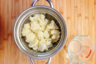 Paleo Cauliflower in a pot on a wood surface, perfect for making Low Carb cauliflower mashed potatoes.