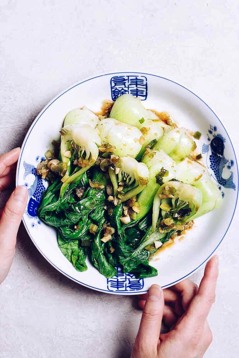 Photo shows baby bok choy after blanched with dim sum sauce on top of a white and blue plate.