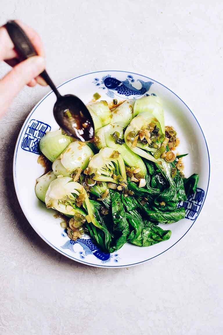 Photo shows drizzling the dim sum ginger garlic sauce over the blanched vegetable. 