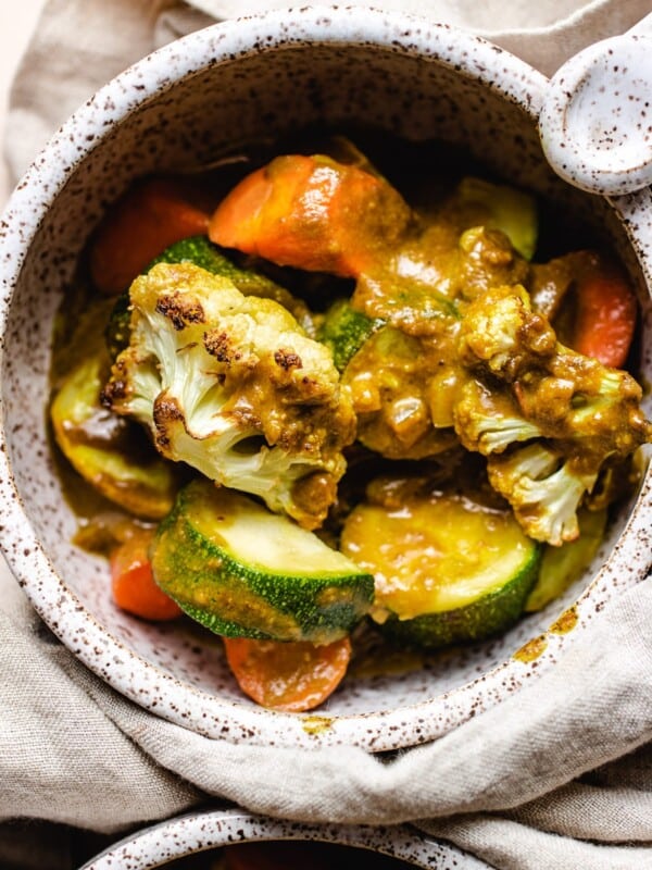 A close shot of photo shows roasted plant-based vegetables with curry sauce