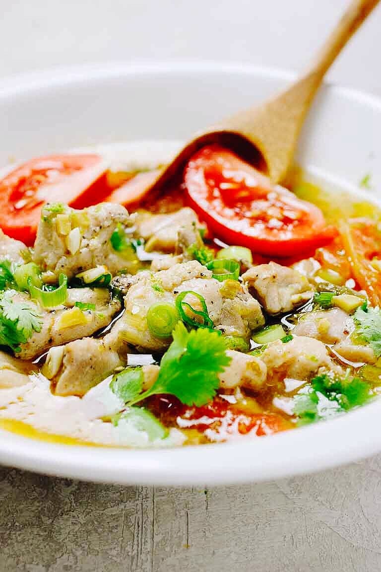 Paleo Chicken Pho Soup recipe with tomatoes, simmered with juicy chicken thighs and lemon and lime zest in a clear chicken broth.