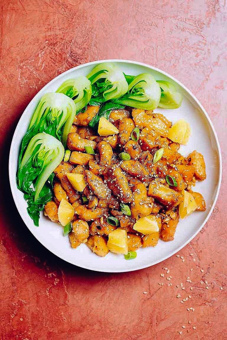 Baked Chinese-style orange chicken served with baby bok choy in a large white plate