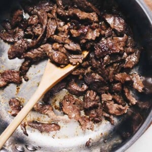 Photo shows thinly sliced tender beef stir-fried in a saute pan