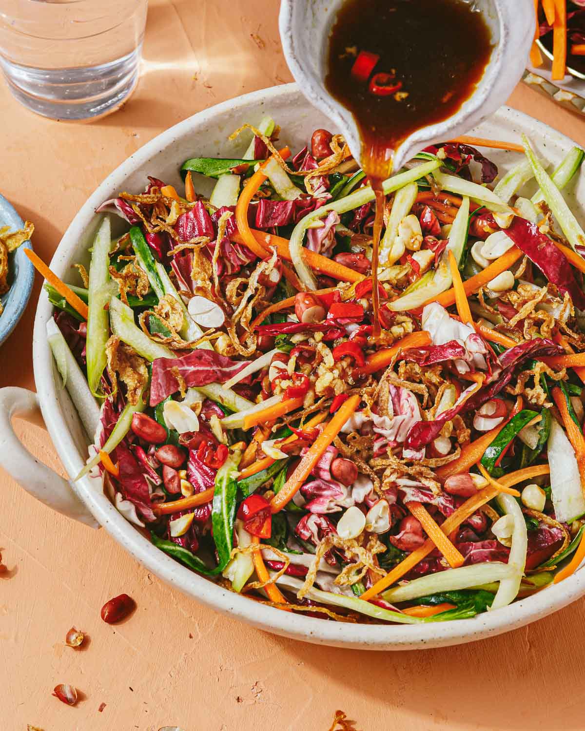 A side close shot shows pouring the Thai dressing over a big plate of coleslaw salad.