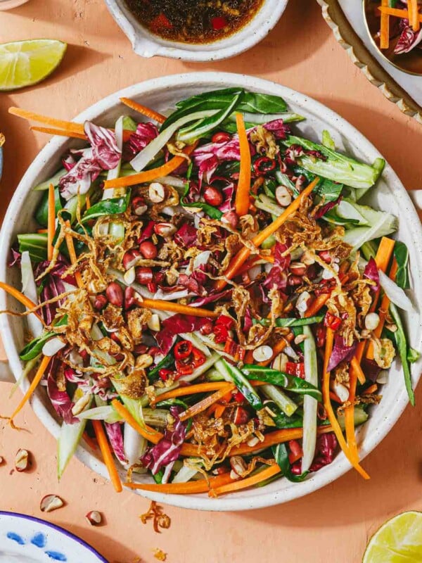 Feature image shows bok choy slaw with other Asian coleslaw vegetables in a large white serving plate and Thai chili dressing on the side.