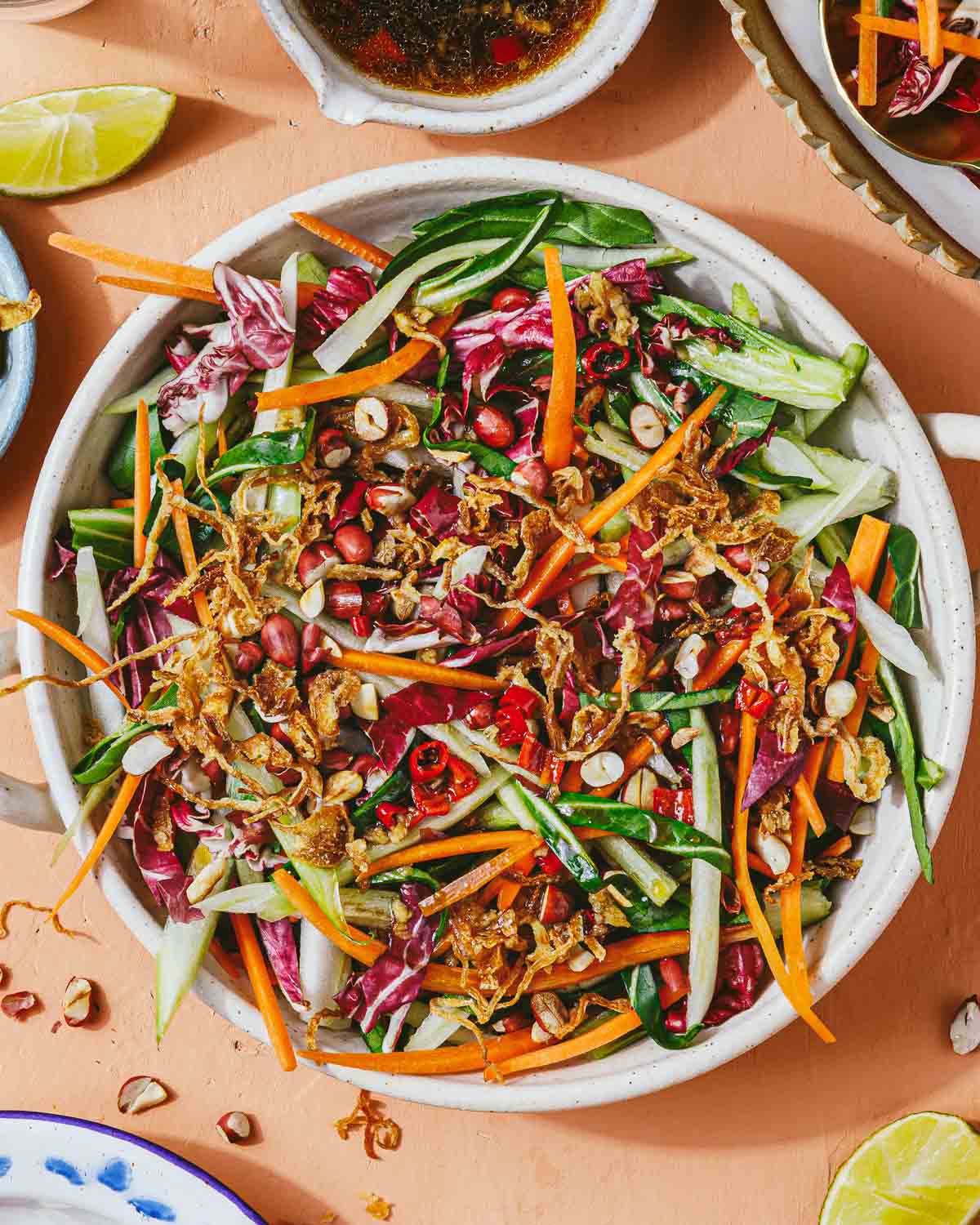 Feature image shows bok choy slaw with other Asian coleslaw vegetables in a large white serving plate and Thai chili dressing on the side.