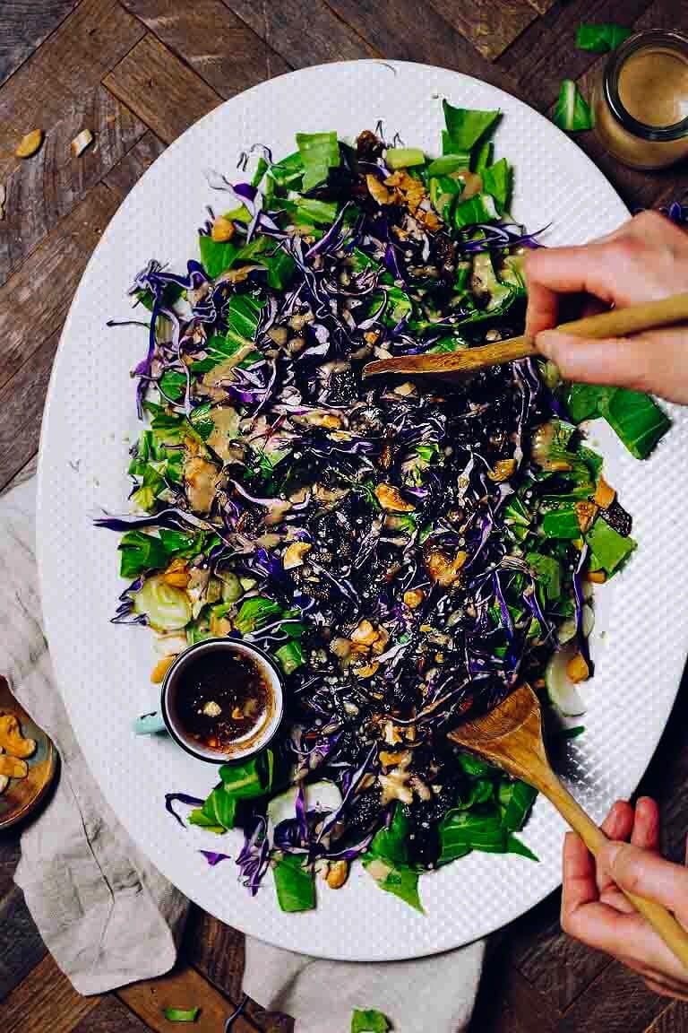 Chopped bok choy with purple cabbage and salad dressing served on a big white plate.