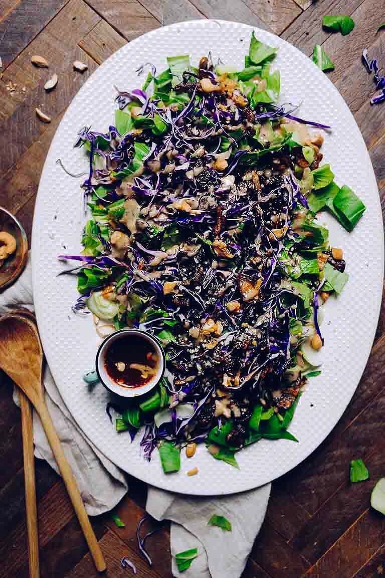 Photo shows Thai style chopped bok choy salad with salad dressing on the side over a big white oval plate.