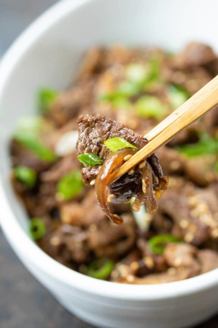 A close short image shows picking up a thin sliced bulgogi beef with chopsticks.