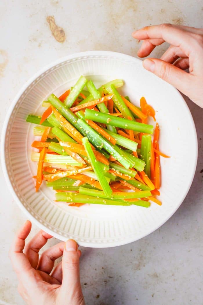 Feature image shows carrots and celery julienned and seasoned as a cold salad, served in a white color bowl.