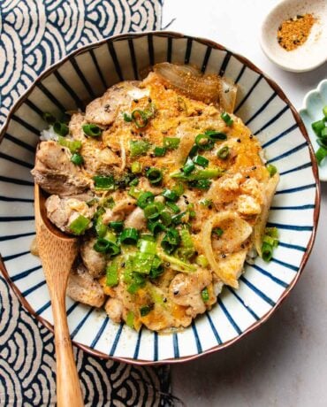 An overhead image shows chicken and egg in a bowl served over a bowl of steamed rice.