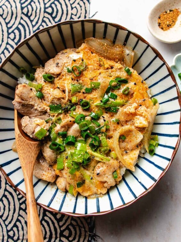 An overhead image shows chicken and egg in a bowl served over a bowl of steamed rice.