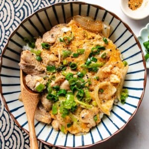 Recipe image shows chicken donburi served over white rice in a blue white color bowl.