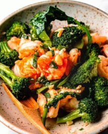A close shot image shows shrimp and broccoli in garlic sauce stir fried and served on a plate.