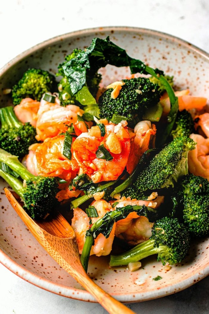 A close shot image shows shrimp and broccoli in garlic sauce stir fried and served on a plate.