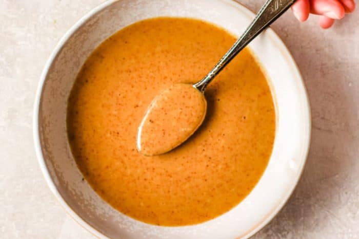 Holding a spoon to show the texture of the Paleo Asian peanut sauce