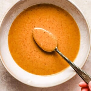 Holding a spoonful of almond butter made peanut flavored sauce