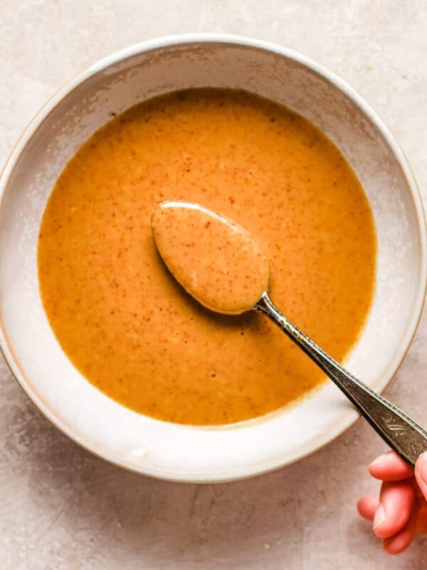 Holding a spoonful of almond butter made peanut flavored sauce