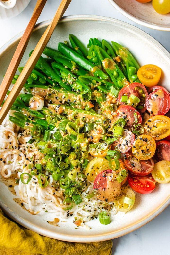 A close shot showing the shirataki noodles and vegetables with the dressing on a plate