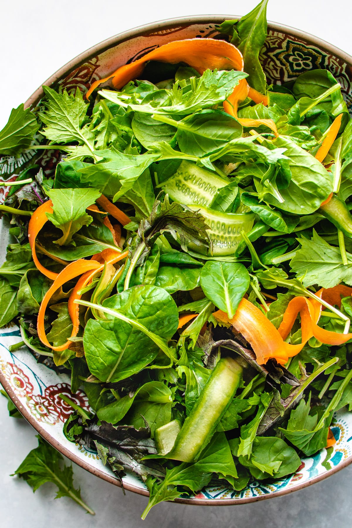 Photo shows a big bowl of fresh Asian salad greens with baby tatsoi lettuce mixed in a large bowl.