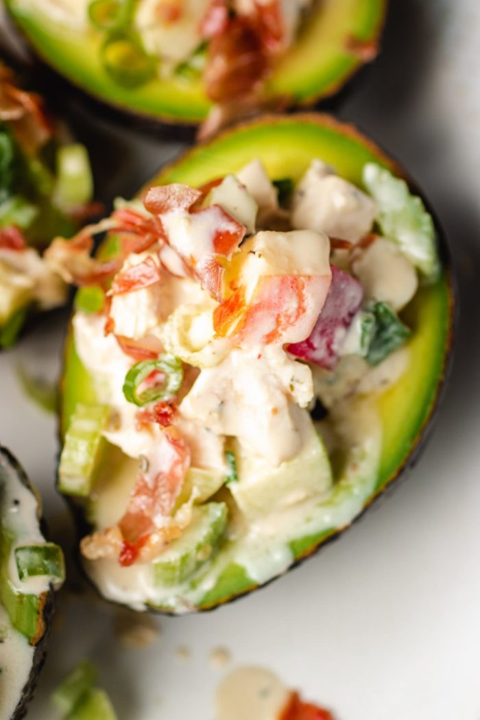A super close shot of one stuffed avocado filled with apple chicken and the dressing