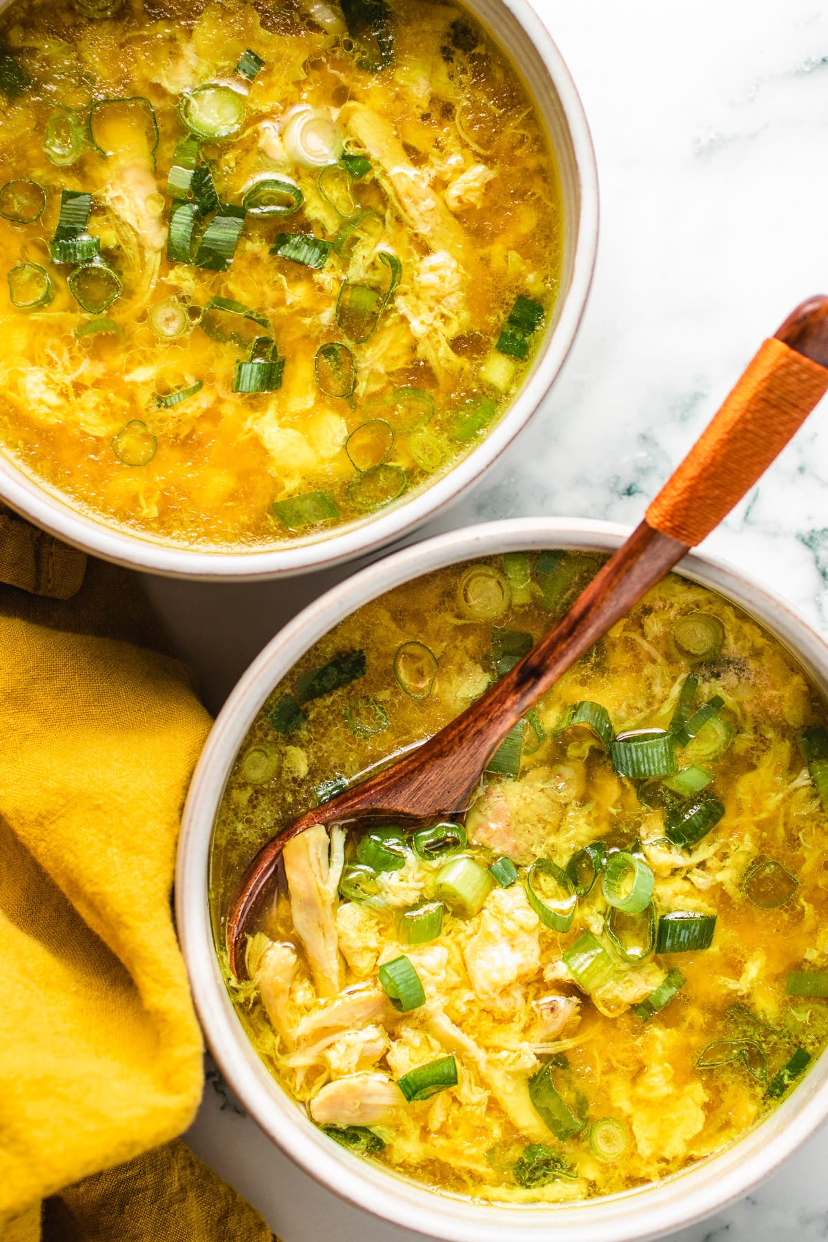 Feature photo with two bowls of keto egg drop soup served in white color bowls with fluffy egg flower ribbons.