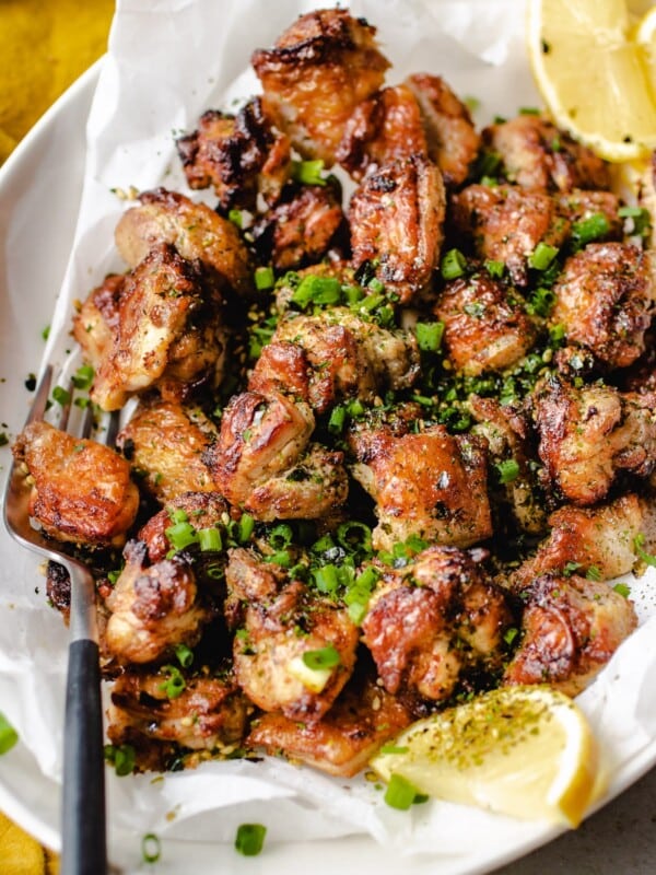 Air fried chicken thigh bites served with lemons over an oval plate