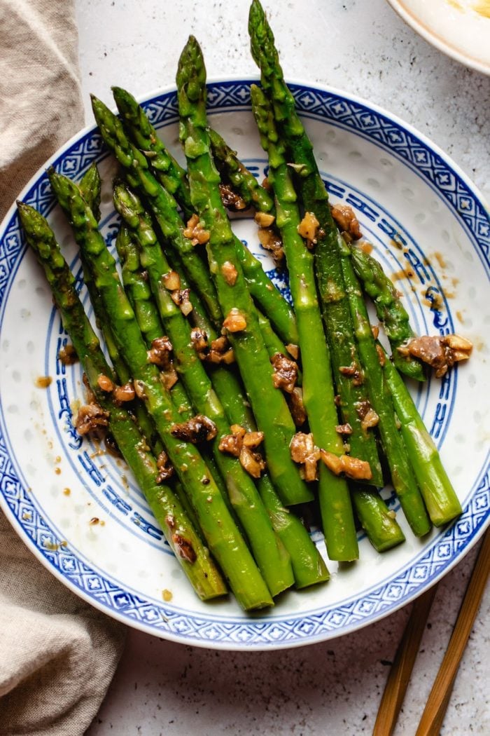 Asparagus served in a blue white plate with chopsticks