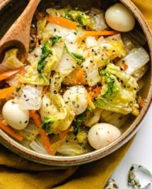 Stir-fried napa cabbage with quail eggs in a ceramic bowl