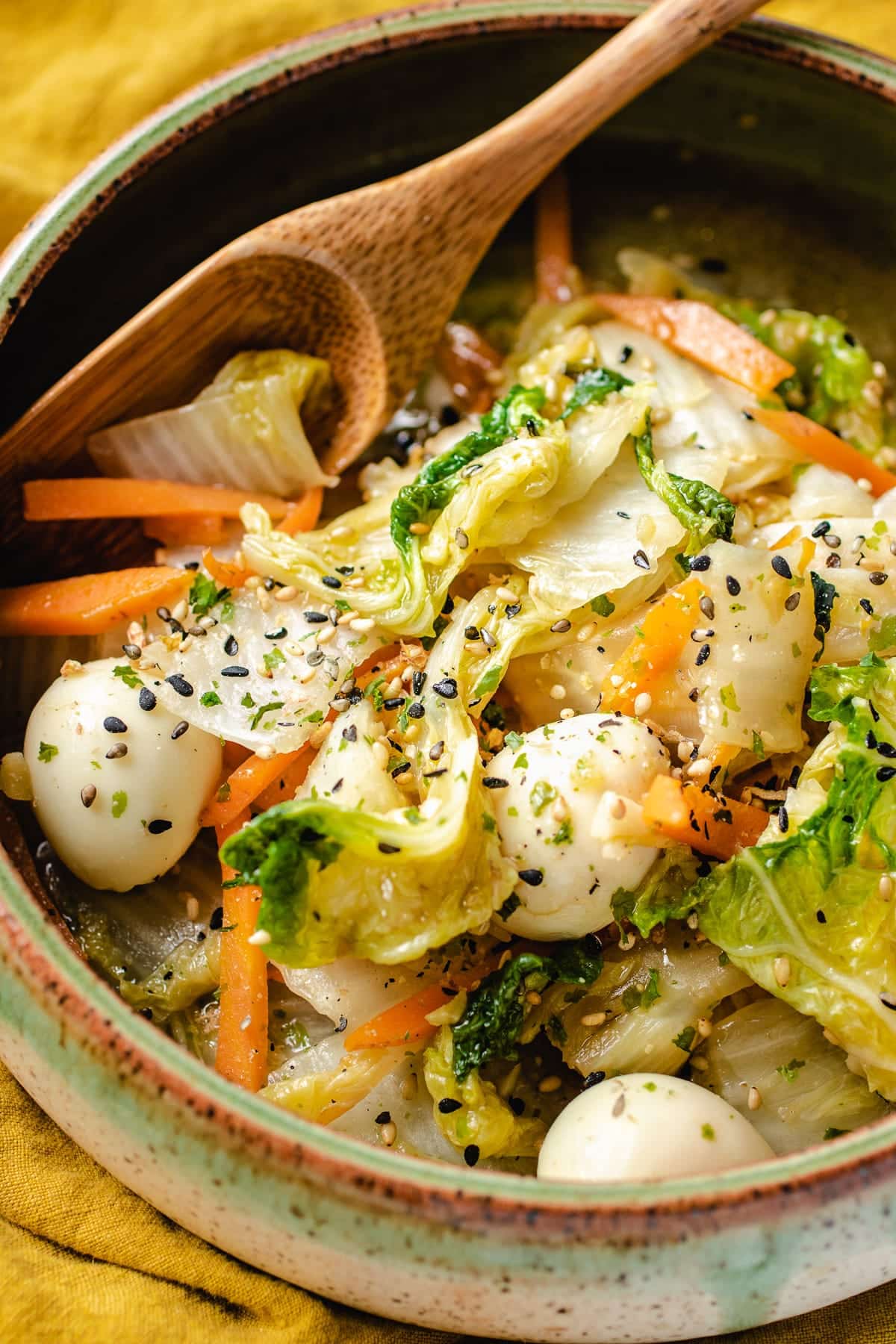 Sauteed Napa Cabbage with quail eggs served in a green bowl