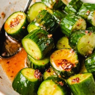 Diced cucumbers tossed in chili honey sauce in a white bowl