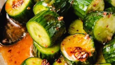 Diced cucumbers tossed in chili honey sauce in a white bowl