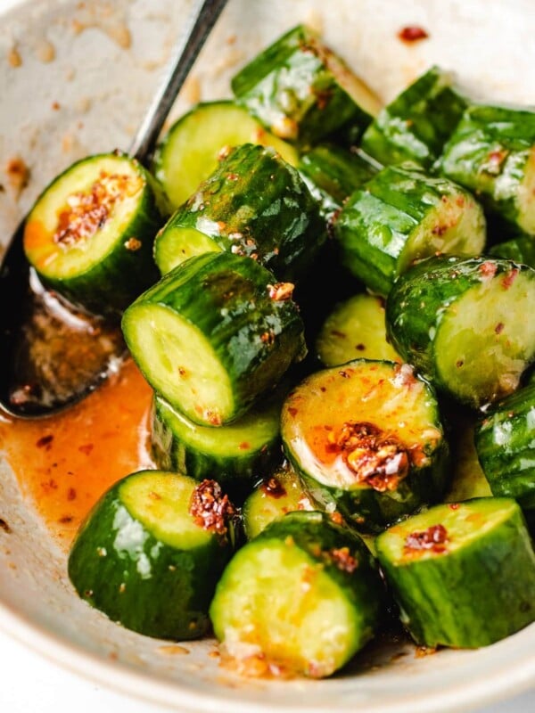 Diced cucumbers tossed in chili honey sauce in a white bowl