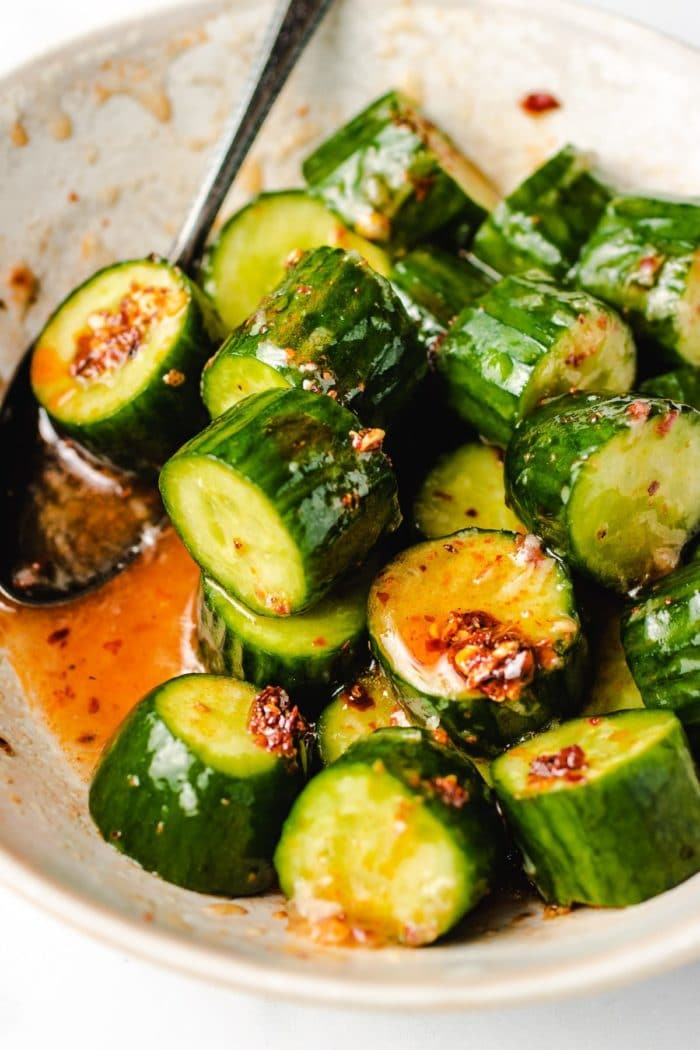 Diced cucumbers tossed in chili honey sauce in a white bowl