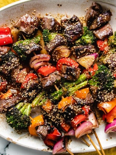 Grilled beef and vegetable kabobs on a big white plate