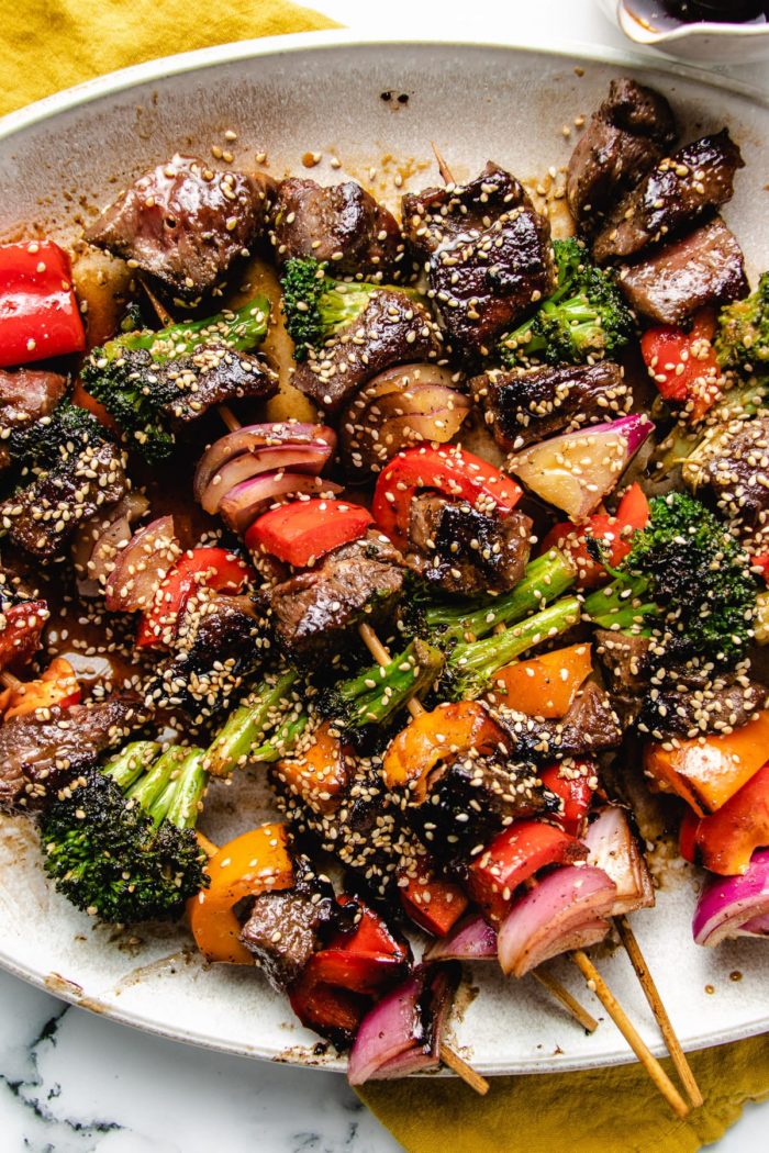 Grilled beef and vegetable kabobs on a big white plate