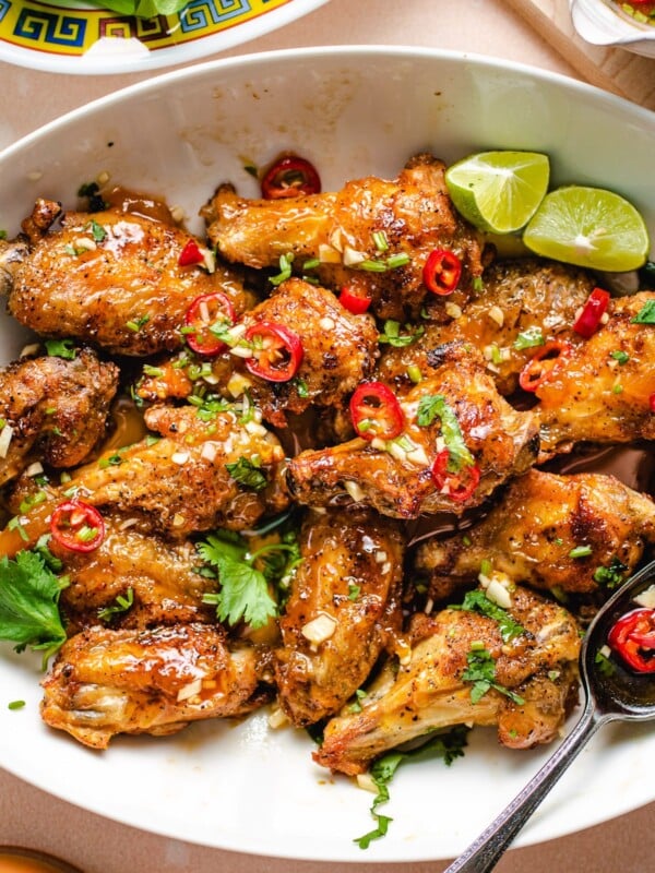 Feature image shows fish sauce wings air fried to crispy and tossed with Vietnamese sweet chili sauce served on a white plate.