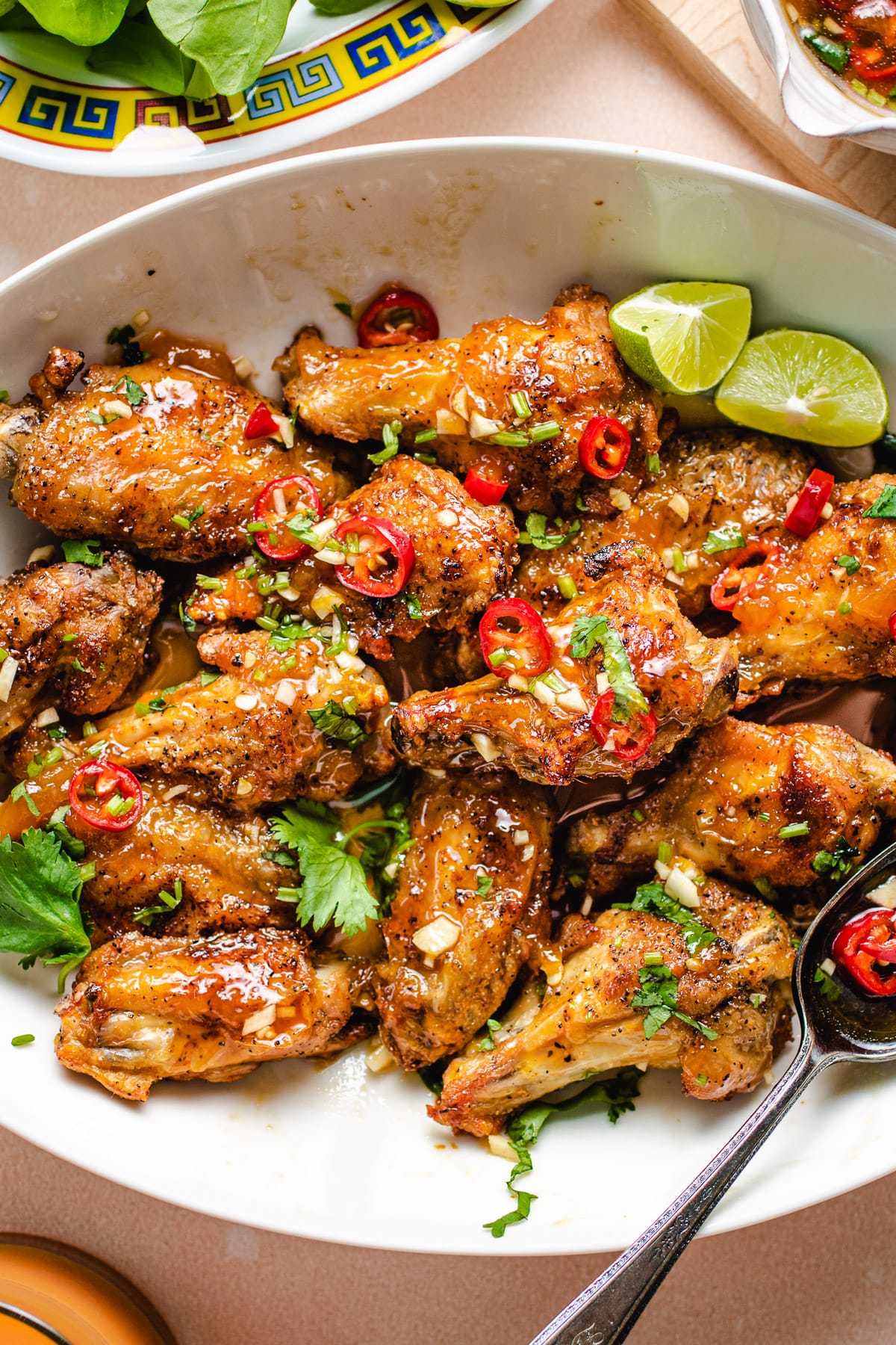 Feature image shows fish sauce wings air fried to crispy and tossed with Vietnamese sweet chili sauce served on a white plate.