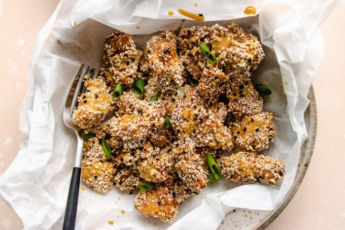 A finished dish served over a white plate with parchment paper under