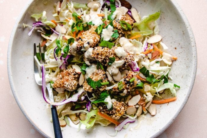 Sesame Chicken with coleslaw salads in a white plate